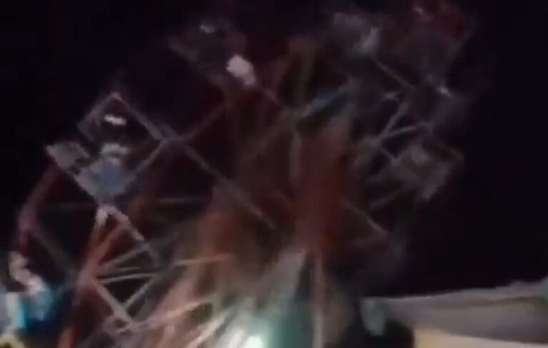 Estructura de una vuelta al mundo (rueda de la fortuna) colapsada en el suelo de una feria, con equipos de emergencia en el lugar.