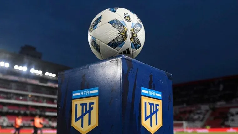 Pelota de fútbol en el centro del campo con estadio de fondo