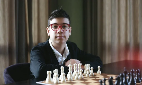 Faustino Oro, niño ajedrecista argentino, sonriendo frente a un tablero de ajedrez
