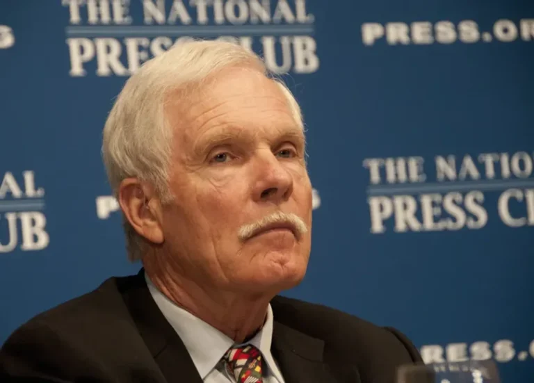 Ted Turner sonriendo en una conferencia de prensa